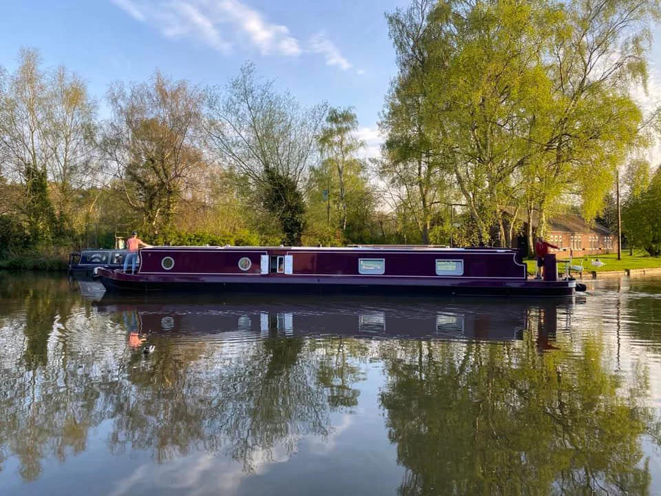 All Good Things, a bespoke KBW narrowboat, reflected in the still water at Kings Bromley